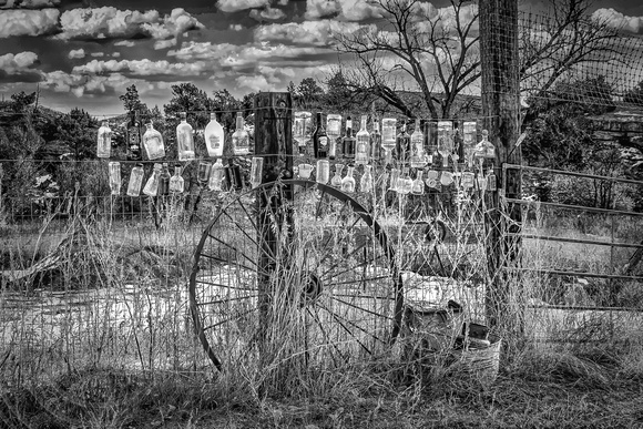 Bottles on fence and spoked wheel-Roundup MT-1-27-2024-bw